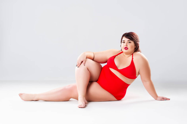 Plus size fashion model in red swimsuit, fat woman in lingerie on gray background, body positive concept - Foto, afbeelding