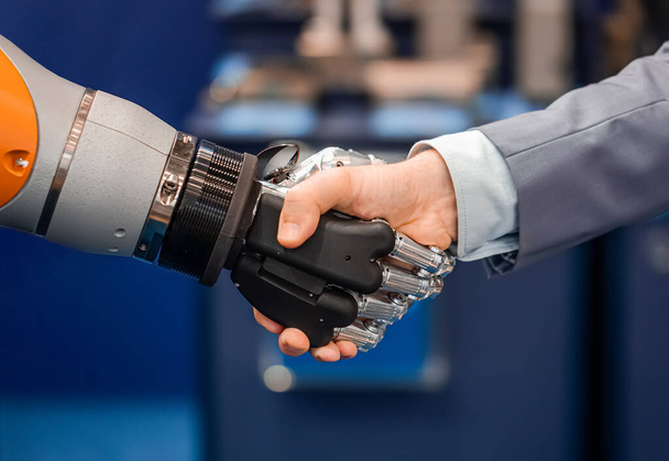 Hand eines Geschäftsmannes beim Händeschütteln mit einem Android-Roboter. Das Konzept der menschlichen Interaktion mit künstlicher Intelligenz. - Foto, Bild