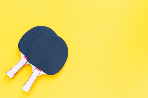 黄色の背景に隔離された黒のテニスピンポンラケット、卓球のためのスポーツ機器 - 写真・画像