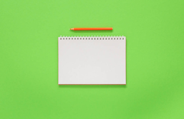Aufgeklappter Spiralblock auf grünem Hintergrund, Notizbuch und Stift liegen auf Texturpapier, flaches Lagekonzept - Foto, Bild