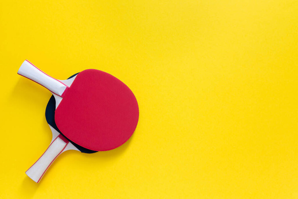 Czerwone i czarne rakiety do ping ponga odizolowane na żółtym tle, sprzęt sportowy do tenisa stołowego - Zdjęcie, obraz