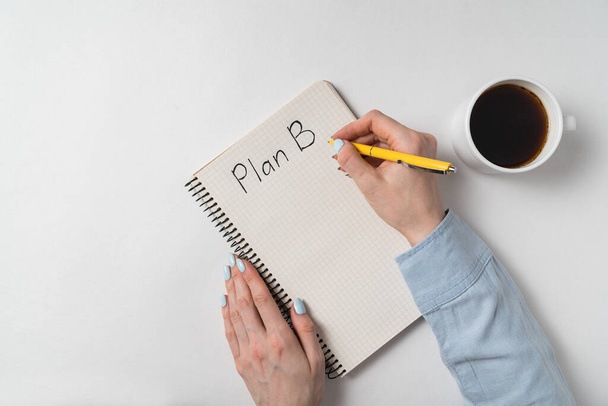 Plan B written on notebook over white background. Female hands and notepad near Cup of coffee. - Fotografie, Obrázek