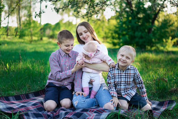 Doğada mutlu bir aile. Aile yaz pikniği parkta. Genç anne ve üç çocuk. - Fotoğraf, Görsel