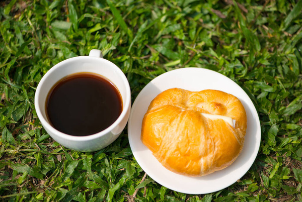 白いカップと黒のコーヒーとクロワッサンチーズ - 写真・画像