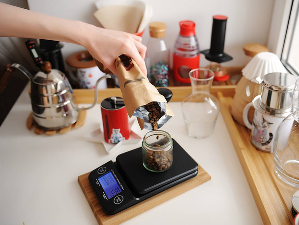 Alternative manual brewing bar. Pouring coffee beans into glass jar on scale. Home barista. Coffee devices - Photo, Image