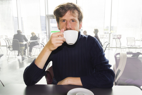 カフェでコーヒーを飲む若い男 - 写真・画像