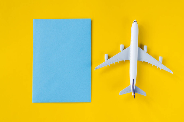 Κενό μπλε χαρτί σε κίτρινο φόντο με διακοσμητικό αεροπλάνο. Καλοκαιρινά ταξίδια. - Φωτογραφία, εικόνα