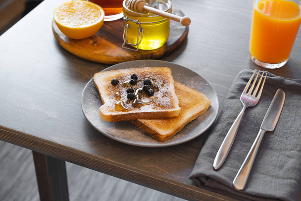 Toast au miel et aux baies. Pot de miel avec trempette et orange sont sur fond. Concept de petit déjeuner sain
. - Photo, image