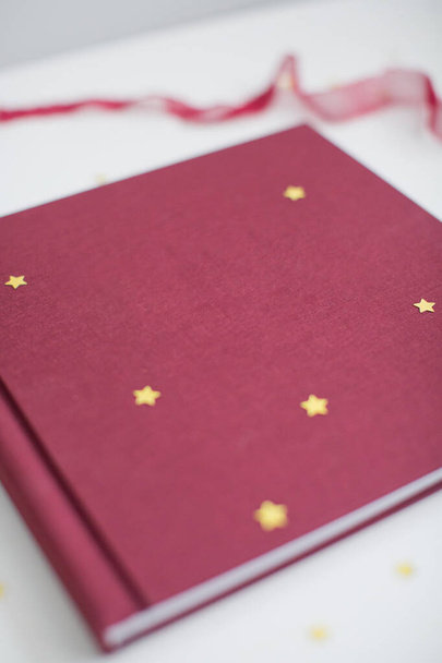 Tkanina marsala książka lub album do zdjęć z dekoracjami wstążki i złote confetti - Zdjęcie, obraz