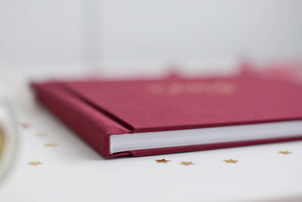 Cloth marsala βιβλίο ή άλμπουμ για φωτογραφίες με διακοσμήσεις από κορδέλα και χρυσά κομφετί - Φωτογραφία, εικόνα
