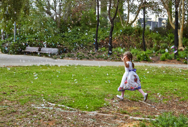 Słoneczny dzień szczęśliwa dziewczynka z wieloma bańkami mydlanymi - Zdjęcie, obraz