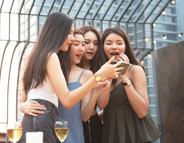 gruppo di giovani amiche che si divertono guardando qualcosa di divertente sul loro smart phone e ridendo mentre fanno festa sul night club sul tetto
 - Foto, immagini