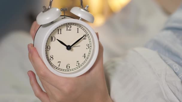 Kobiece ręce trzymające budzik i ustawiające małą dłoń na sześć godzin. Zbliżenie - Materiał filmowy, wideo