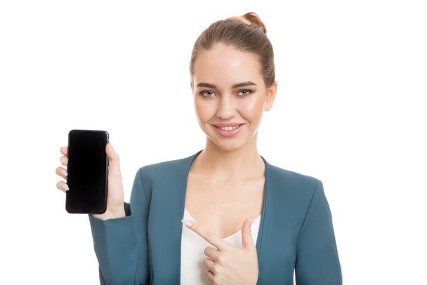Szczęśliwa bizneswoman trzymająca w ręku smartfona wskazującego na niego. Oddzielnie na białym tle. - Zdjęcie, obraz