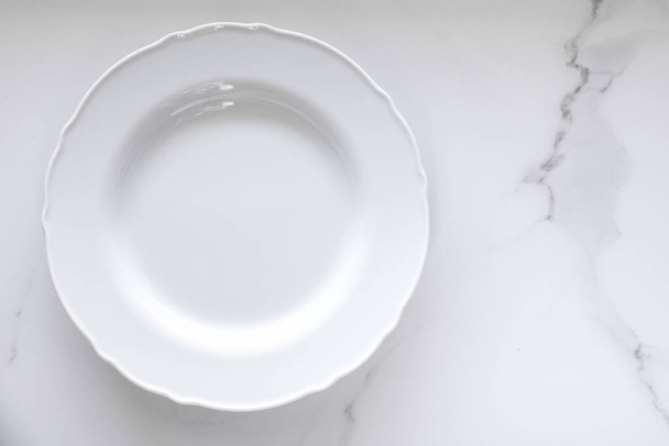 Placa vacía sobre mesa de mármol blanco como fondo, comida y menú
 - Foto, imagen