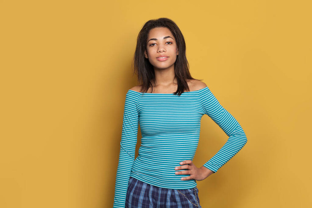 Uma mulher afro-americana bonita. Menina bonito em camisa azul listrado no fundo amarelo
 - Foto, Imagem