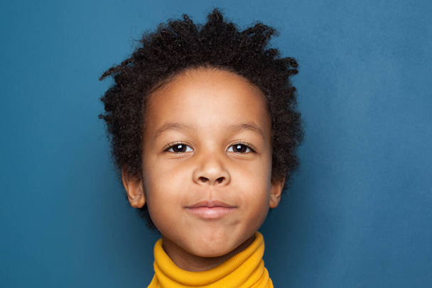 Afrikkalainen amerikkalainen lapsi poika kasvot lähikuva sinisellä taustalla
 - Valokuva, kuva