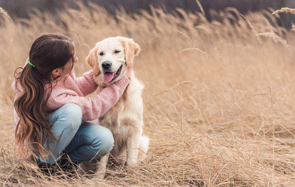 Happy girl petting young dog - Фото, зображення