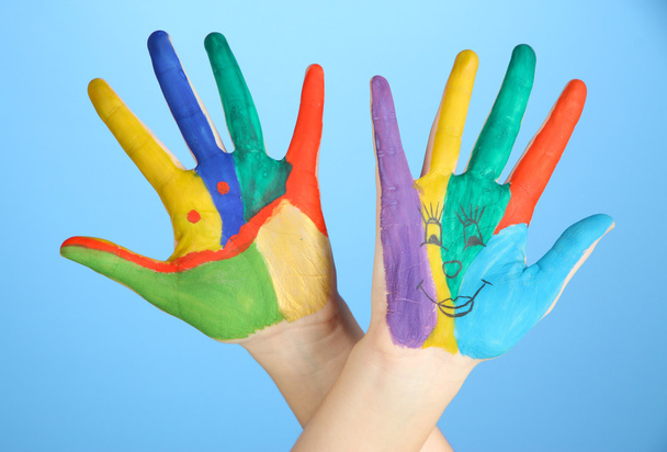 Painted hands with smile on blue background - 写真・画像
