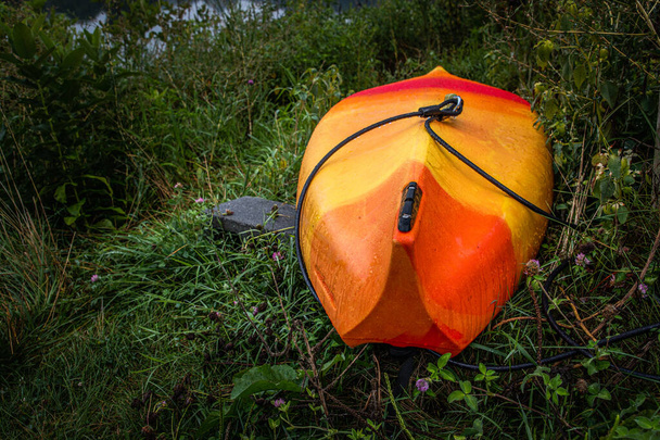 An upside-down bright orange kayak awaits its owner at Speedwell Forge Lake in eastern Pennsylvania - Photo, Image