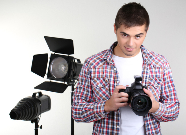Handsome photographer with camera, on photo studio background - Φωτογραφία, εικόνα