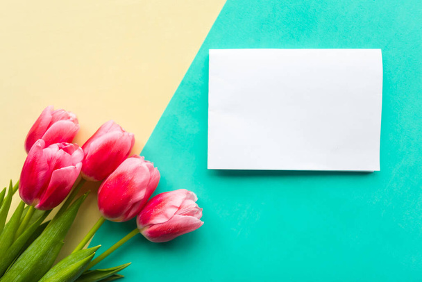pink tulips and white mockup blank on yellow and green background. Easter or Mother's Day greeting card. Copy space for the text - Foto, Bild