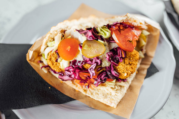 Falafel kebab in gefokt op heldere achtergrond, fast food  - Foto, afbeelding