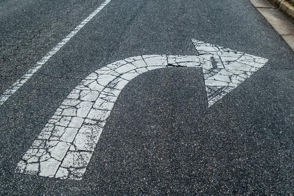 Un giro a destra solo freccia dipinta di bianco sull'asfalto incrinato e consumato dal traffico sulla strada all'aperto
 - Foto, immagini