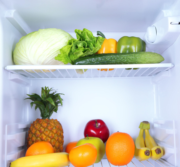 Milk bottles, vegetables and fruits in open refrigerator. Weight loss diet concept. - Fotó, kép