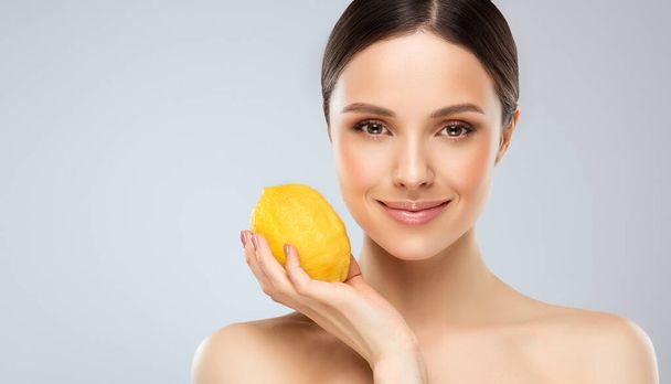 Pretty cheerful emotional young woman posing with a juicy lemon vegetable.Vegan lifestyle. Smiling girl , eating concept.Diet organic , weight loss and healthy food. Smoothies and fresh juice. - Foto, afbeelding