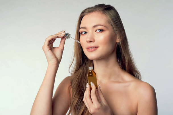 beautiful model applying a skin serum treatment on white. Spa, skincare and wellness. Close up, copyspace - Фото, изображение