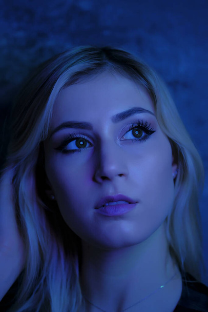 beautiful girl portrait blonde dark eyes with colored lights - Photo, Image