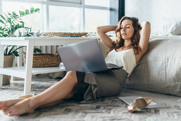 Jeune femme se relaxe et utilise un ordinateur portable à la maison
 - Photo, image