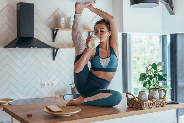 Giovane donna beve latte e fa un esercizio di stretching
. - Foto, immagini