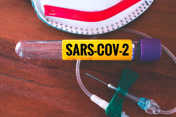 Exame de sangue com máscara facial e cânula e tubos sanguíneos para a epidemia de corona e inscrição SARS-COV-2
 - Foto, Imagem