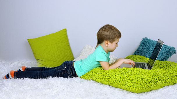 Little boy with laptop on bed - Foto, afbeelding