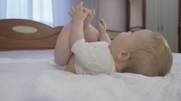 Aranyos baba, kék szemekkel az ágyon fekszik. - Felvétel, videó