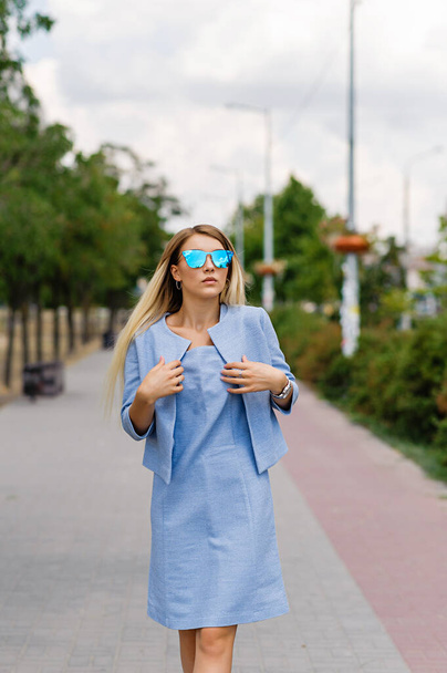 Attractive blonde in a blue dress in the park - Zdjęcie, obraz