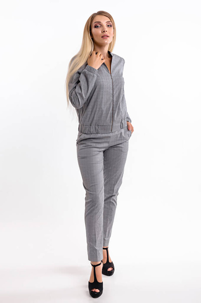 Attractive girl in a trouser suit on a white wall background - Valokuva, kuva