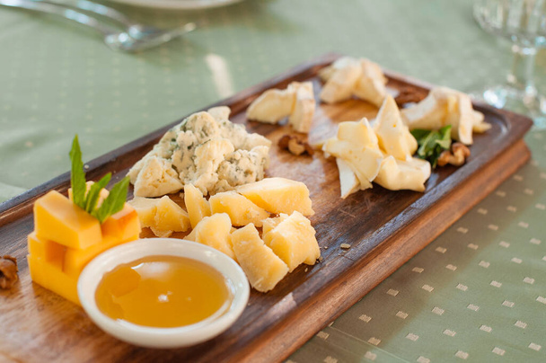 Prato de queijo. Diferentes tipos de queijo com mel em uma tábua de madeira
. - Foto, Imagem