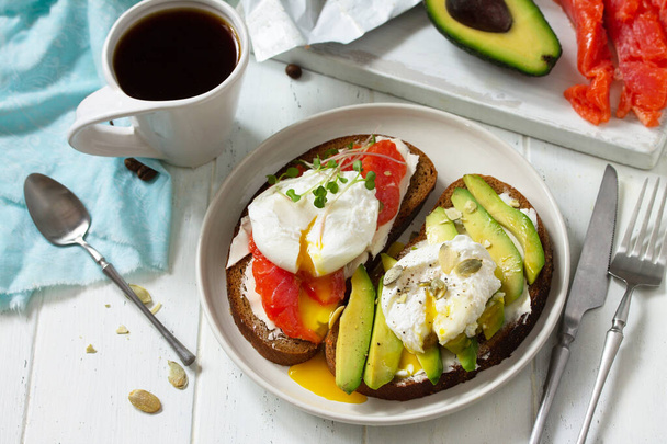 Ранковий сніданок. Варене яйце бутерброд з авокадо, лососем і кавою на дерев'яному столі. Копіювати простір
. - Фото, зображення