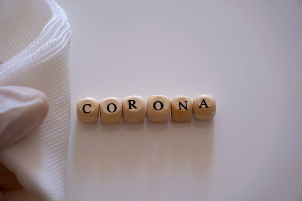 La palabra Corona, una asociación con el término de enfermedad Coronavirus o Covid-19, sobre un fondo blanco bajo gasa médica
 - Foto, Imagen