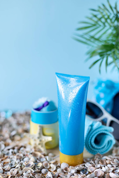Güneş kremi şişeleri, gözlükler, mavi arka planda deniz yıldızı palmiyesi yaprakları. Yazın güzellik ve bakım. - Fotoğraf, Görsel