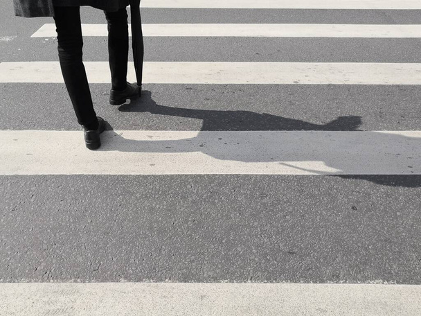 脚と影を持つテクスチャ舗装の背景市民は、ゼブラクロスウォークでアスファルト道路を横断 - 写真・画像