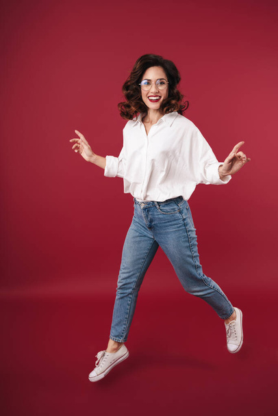 Photo of amazing happy young woman jumping isolated over red wall background. - Fotografie, Obrázek
