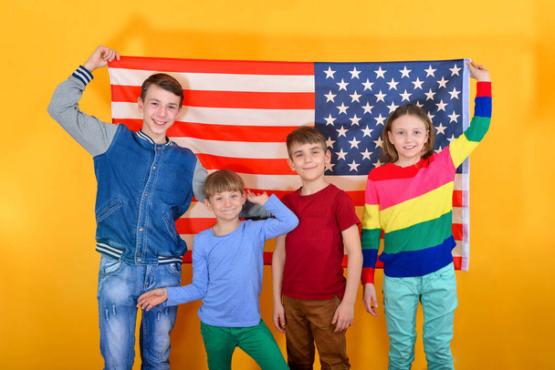 Gelukkige en vreugdevolle kinderen die de Amerikaanse vlag voeren, het concept van bescherming en bescherming van de Usa. - Foto, afbeelding