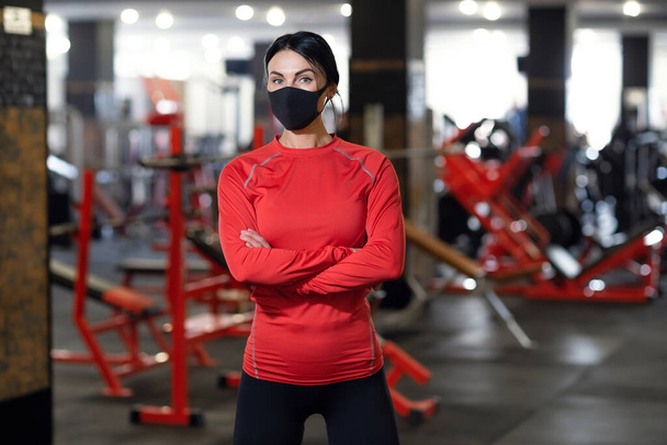 Coronavirus covid-19 prevention, fitness girl with a medical mask posing in gym. Fighting viruses - Fotoğraf, Görsel