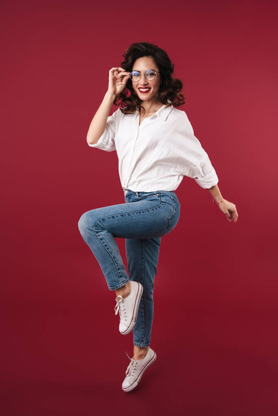 Photo of amazing happy young woman jumping isolated over red wall background. - Valokuva, kuva