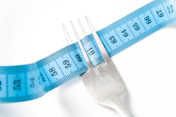 blue measuring tape and fork on a white background diet concept fasting weight loss and slimming - Foto, Bild
