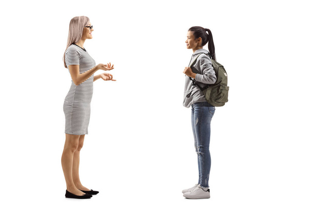 Full length profile shot of a female student and a blond woman having a conversation isolated on white background - Фото, изображение